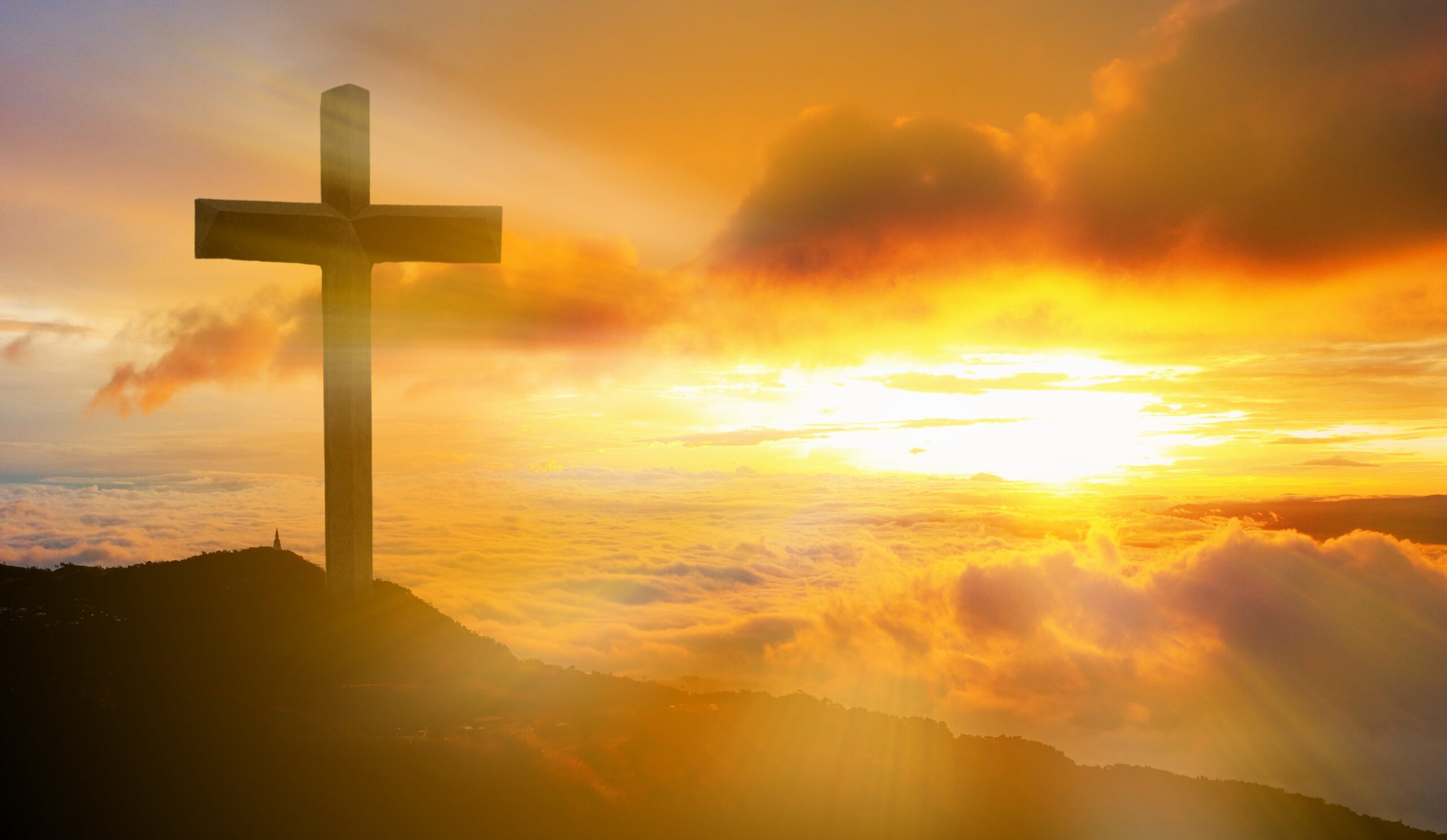 Cross silhouette against vibrant sunset sky.