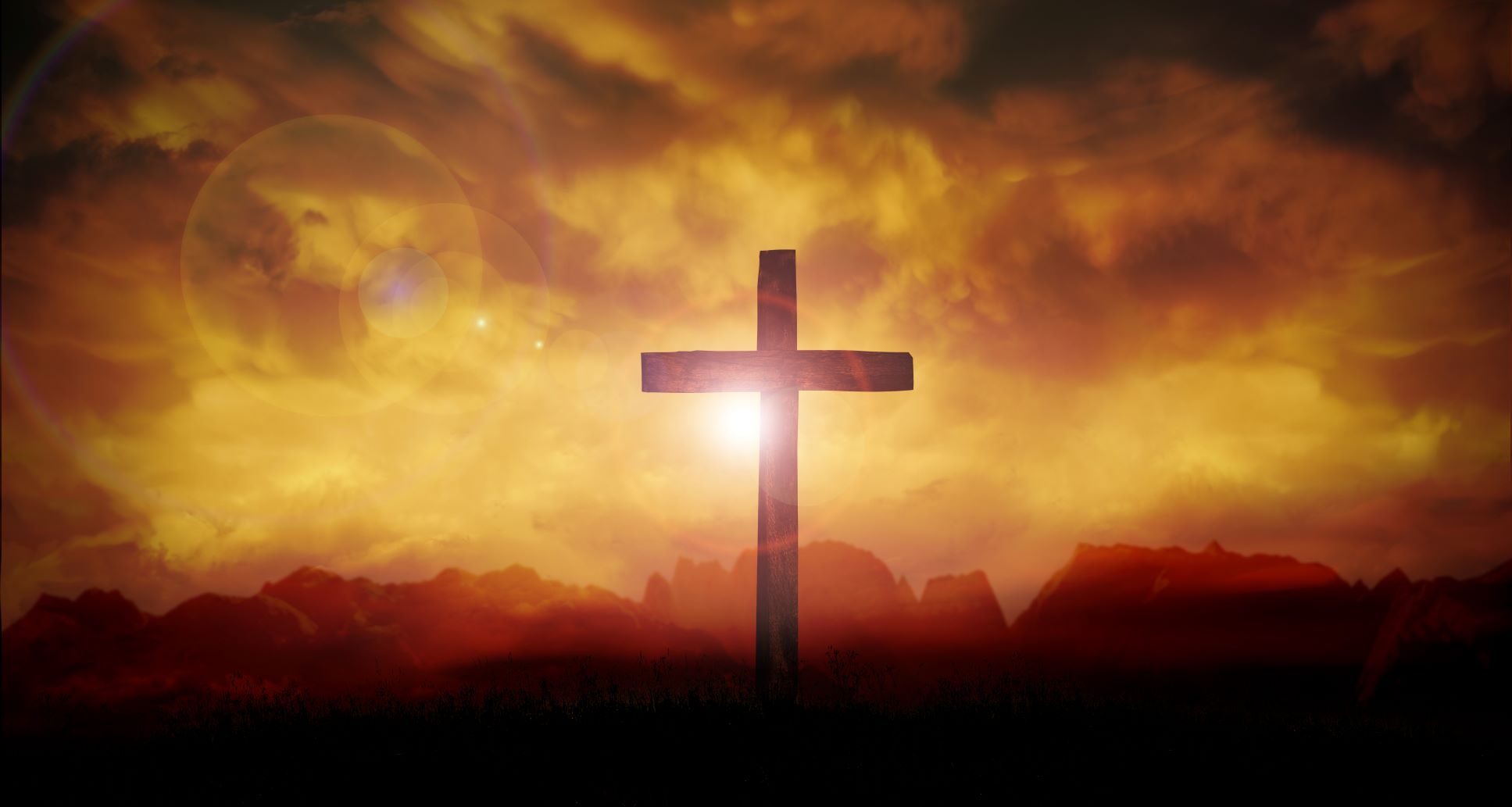 Sunset behind cross silhouette in clouds.