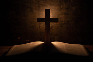 Cross illuminated behind an open book.