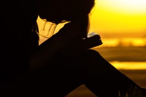 Silhouette reading a book at sunset.